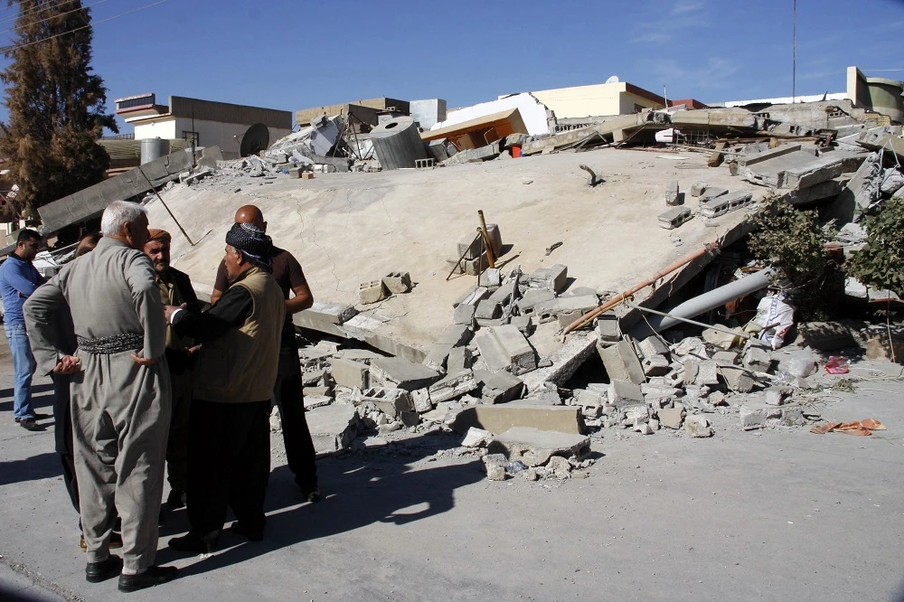People gather around a levelled building in the mountainous town of Darbandikhan in Iraqi Kurdistan on November 13, 2017, following a 7.3-magnitude quake that hit the Iraq-Iran border area. (File photo: AFP)