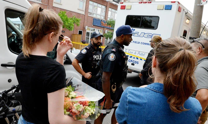 A friend (L) of a victim who died in the previous night's shooting rampage tries to go to the crime scene on July 23, 2018 in Toronto. (AFP)