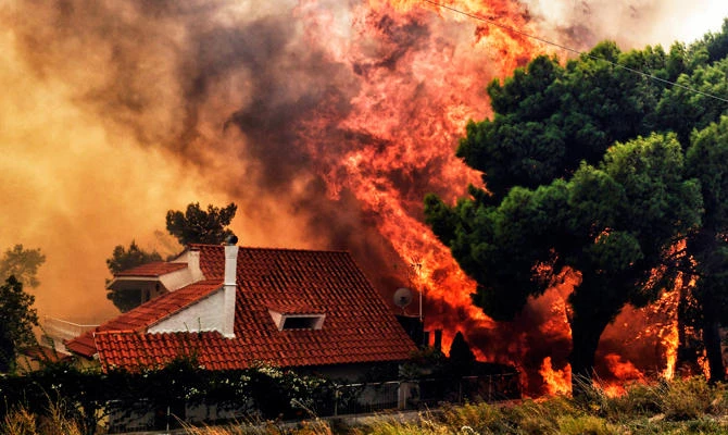 A house is threatened by a huge blaze during a wildfire in Kineta, near Athens, on July 23, 2018. (AFP)