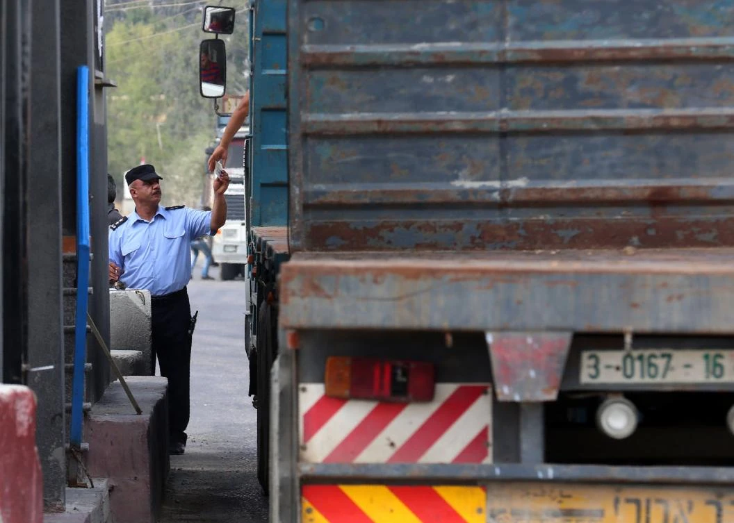 A security officer loyal to the Palestinian Authority checks the documents of a driver at the gate of the Kerem Shalom crossing, the main passage point for goods entering Gaza. (AFP)