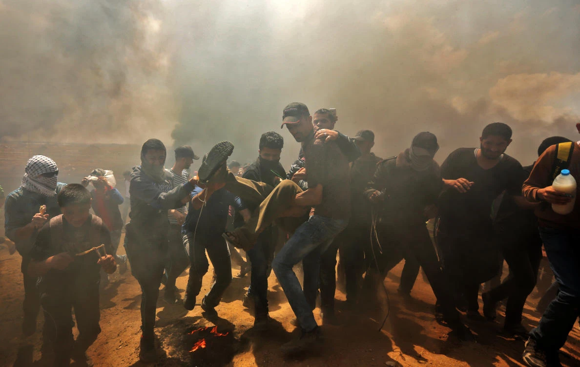 Palestinians carry a demonstrator injured during clashes with Israeli forces near the border between the Gaza strip and Israel east of Gaza City on May 14, 2018. (Mahmud Hams/AFP)