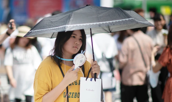 A woman uses a portable fan to cool herself in Tokyo on July 24, 2018, as Japan suffers from a heatwave. (AFP)