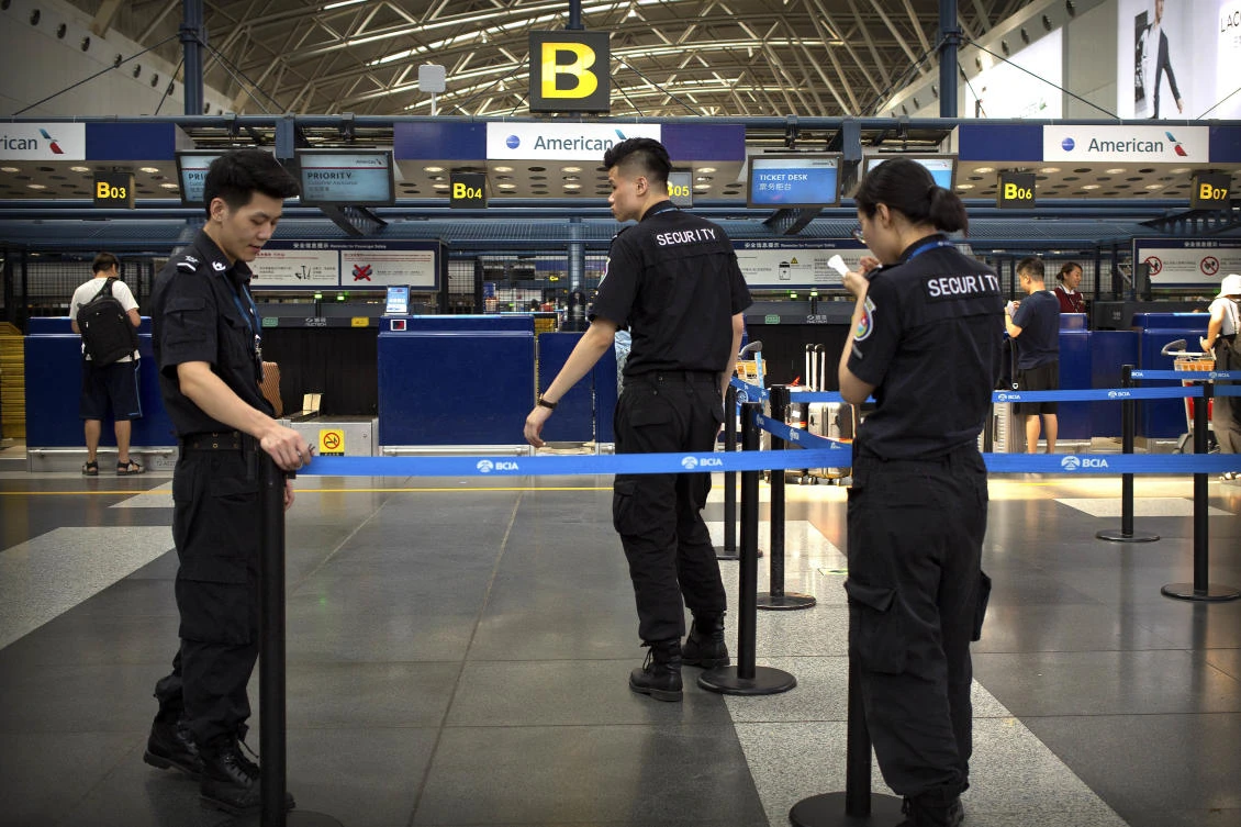 Chinese security personnel stand near the check-in counters for American Airlines at Beijing Capital International Airport in Beijing. (AP)