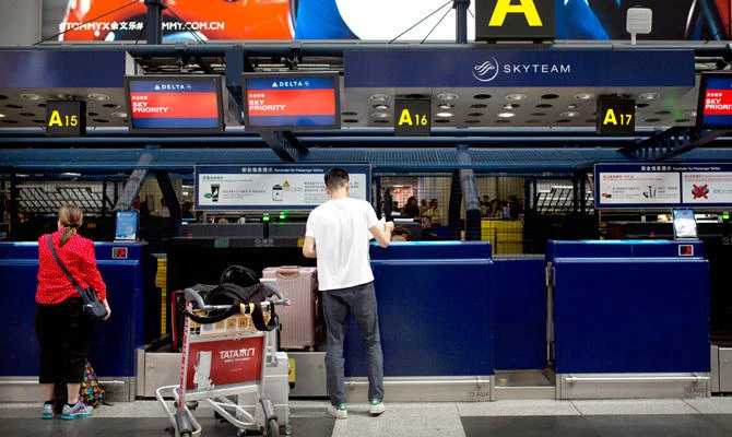 In this July 6, 2018, photo, travelers check in for flights at the Delta Air Lines check-in counters at Beijing Capital International Airport in Beijing. (AP)
