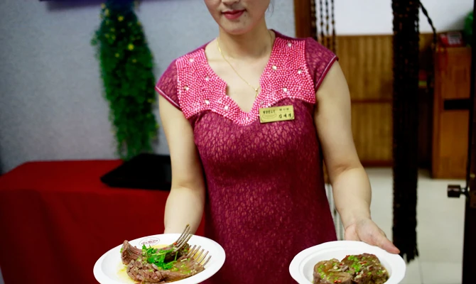 A waitress shows dishes made of dog meat at at Pyongyang House of Sweet Meat, a dog specialty restaurant in Pyongyang, North Korea, Wednesday, July 25, 2018. (AP)