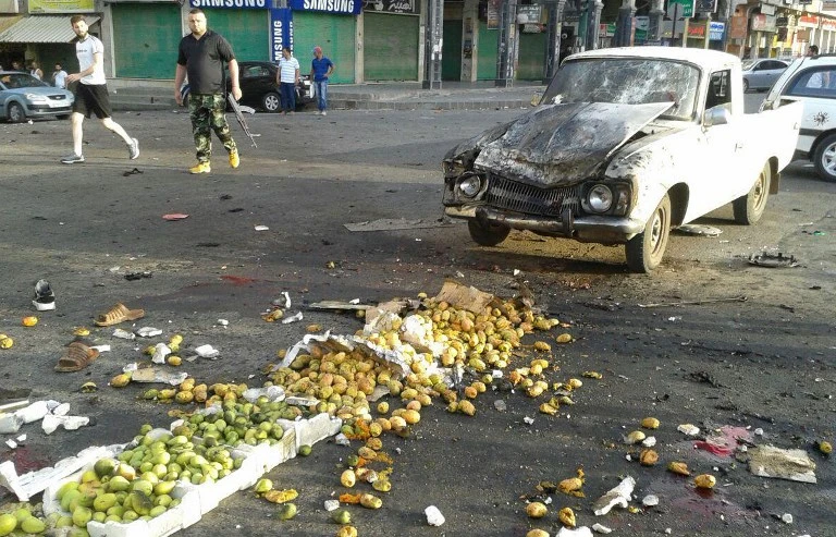 A member of the Syrian security forces walking past a truck damaged in a suicide attack in the southern city of Sweida in this handout photo from the Syrian Arab News Agency on Wednesday, July 25. (AFP)