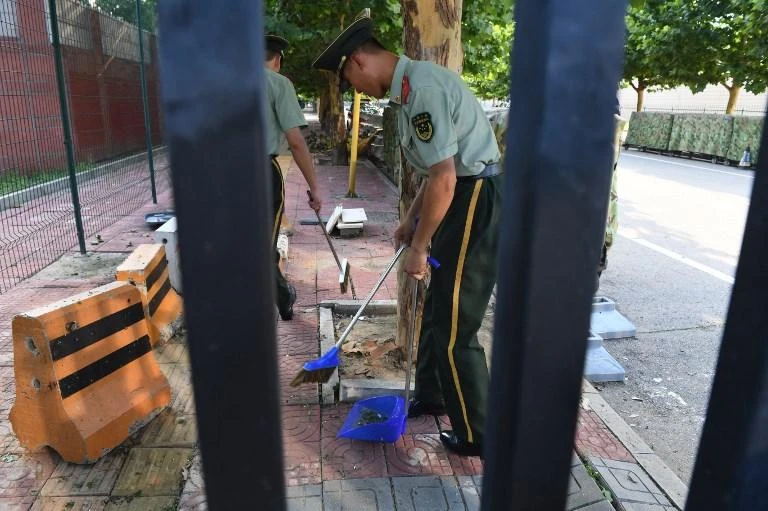 Paramilitary police clean up broken glass and debris outside the US embassy compound in Beijing on Thursday, July 26, 2018 following a blast near the embassy premises. (AFP)