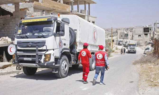 Syrian Arab Red Crescent lorries, carrying humanitarian aid, enter the southern city of Daraa. (AFP)