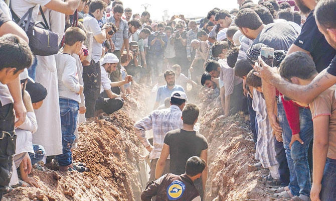 Members of the Syrian civil defence volunteers, also known as the White Helmets, bury their fellow comrades during a funeral in Sarmin, a jihadist-held town nine kilometres east of Syria's northwestern city of Idlib on August 12, 2017. (AFP)