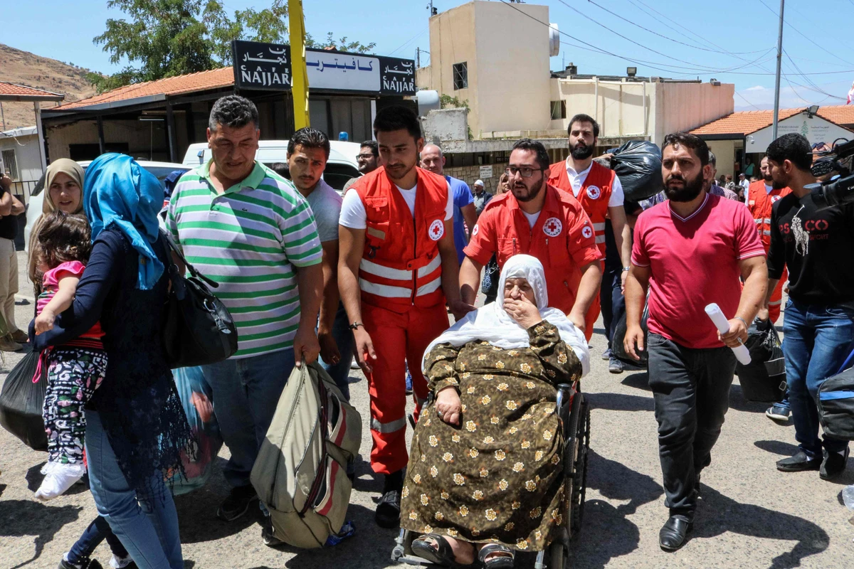 Members of the Lebanese Red Cross escort an elderly Syrian refugee at the Masnaa crossing on the Lebanon-Syria border on July 28, 2018, before her evacuation back to Syria. (AFP)