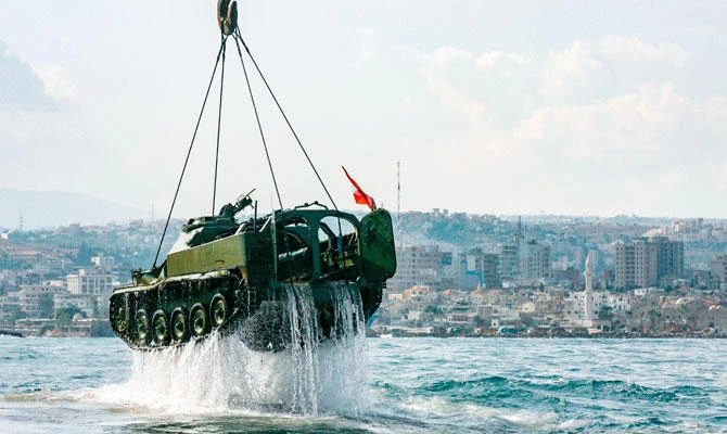 Environmental activists drop off an old mechanised armoured personnel carrier provided by the Lebanese Armed Forces into the Mediterranean Sea, about three kilometres off the coast of the southern Lebanese port city of Sidon, on July 28, 2018, to create new habitat for marine life. (AFP)
