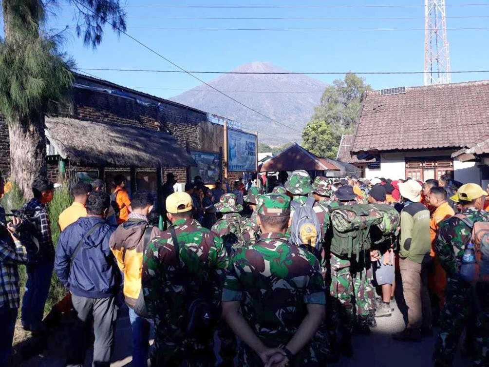 Indonesian soldiers and rescue teams gather to prepare for evacuating tourists from Mount Rinjani, at the background, after a strong and shallow earthquake early Sunday. (AP)