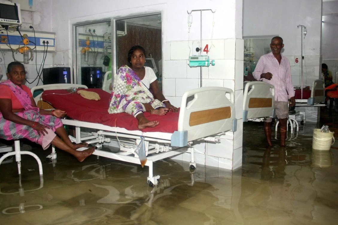 An Indian patient and her relative keep dry in the waterlogged Nalanda Medical College and Hospital in Patna following heavy monsoon rains. (AFP)