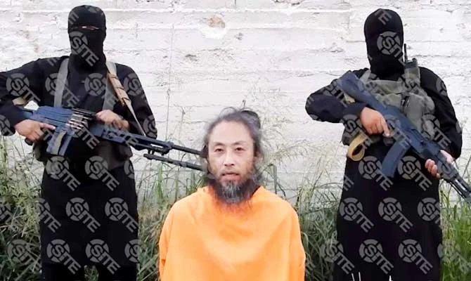 This video image released on July 31, 2018, and provided courtesy of SITE Intelligence Group shows Japanese national, Yasuda Jumpei, appealing for his release as two armed men stand behind him at an unknown location in Syria on the July 25,2018 according to SITE. (AFP)