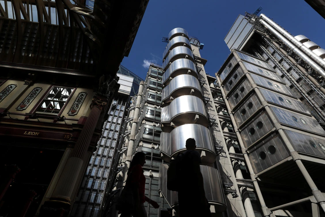 People walk outside Lloyds of London's headquarters in the City of London. (Reuters)
