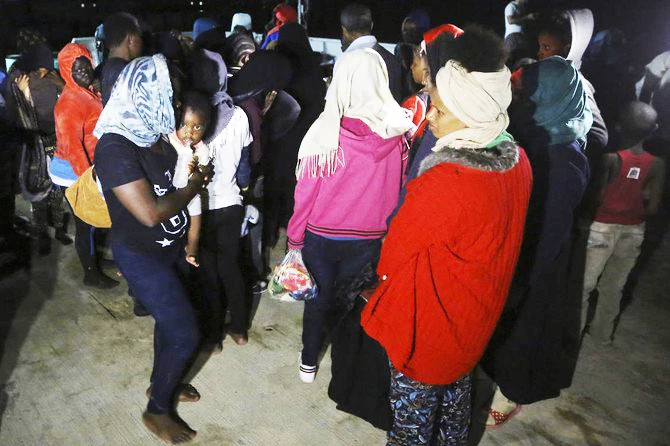 A woman holds a toddler as migrants arrive at a naval base in Tripoli, after being rescued off the coast of Zawia on July 30, 2018. (AFP / Mahmud Turkia)
