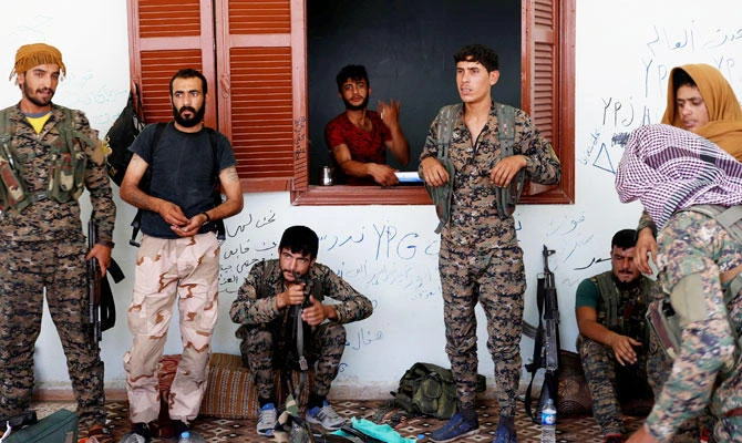 Kurdish fighters from the People's Protection Units (YPG) stand outside a house in Raqqa, Syria. (REUTERS)