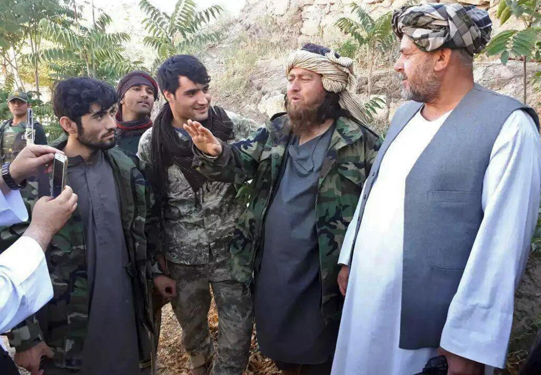 A foreign Daesh fighter, second right, speaks to a journalist after he surrendered to government security forces in the Darzab district of Jawzjan province, north of Kabul, Afghanistan, Wednesday, Aug. 1, 2018. (AP)