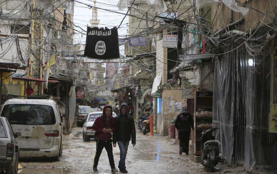 Youth walk under a Daesh flag in Ain al-Hilweh Palestinian refugee camp, near the port-city of Sidon, in southern Lebanon on January 19, 2016. (Reuters)
