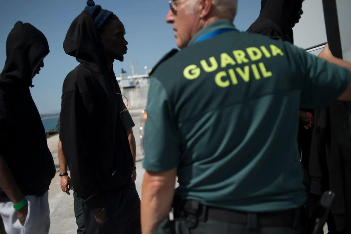 In this file photo, Spanish Guardia Civil members stand guard as migrants disembark from a Spanish coast guard boat carrying 110 people rescued from an inflatable boat in the Mediterranean Sea at the harbor of Algeciras. (AFP)