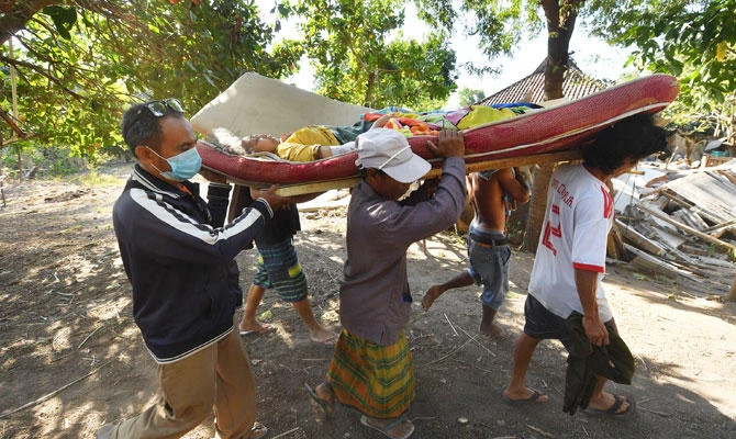 Indonesian people carry an injured woman in Pemenang, North Lombok on August 6, 2018, the day after a 6.9 magnitude earthquake struck the area. (AFP)