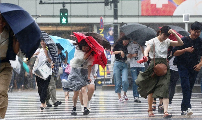 In this photo taken on July 28, 2018, people protect themselves with umbrellas as heavy rains caused by Typhoon Jongdari fall in Tokyo. (AFP)