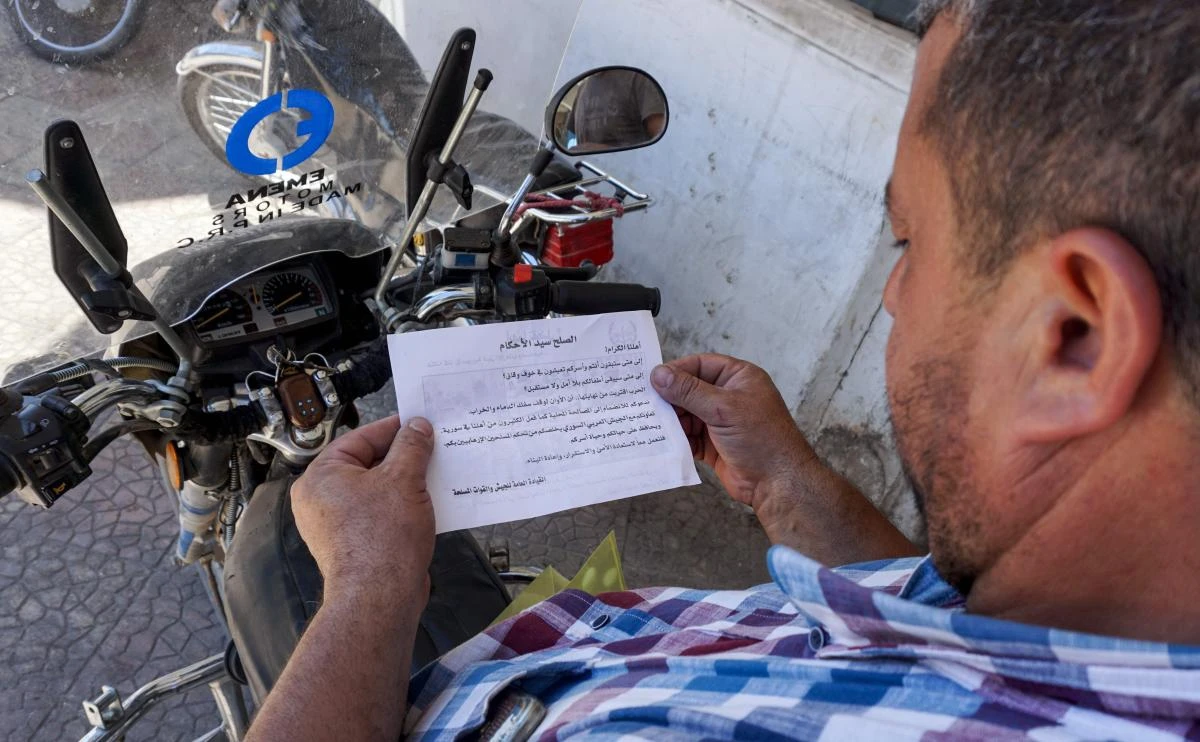 A Syrian man holds a leaflet stamped with the government forces' seal and dropped by helicopters flying over the northwestern Syrian town of Binnish on August 9, 2018 reading in Arabic: "The war is nearing an end... We are calling on you to join the local reconciliations, as many of our people in Syria did. (AFP)
