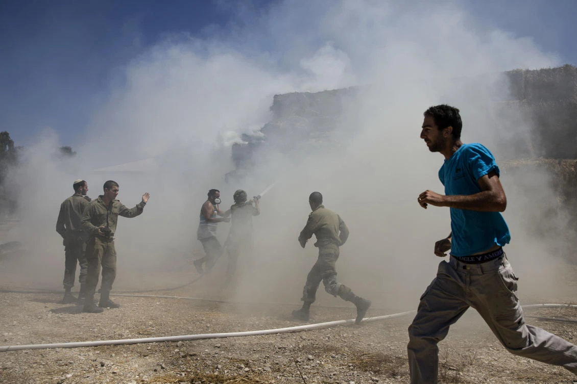 In this July 21, 2018 file photo, Israeli firefighters and soldiers on the Israeli Gaza Border attempt to extinguish a fire caused by a incendiary balloon launched by Palestinians from the Gaza Strip. (AP)