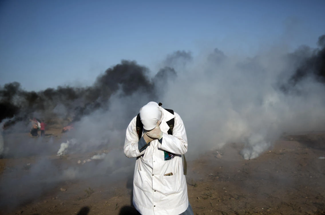 A Palestinian medic reacts from teargas fired by Israeli troops during a protest at the Gaza Strip’s border with Israel, Friday, Aug.10, 2018. (AP)