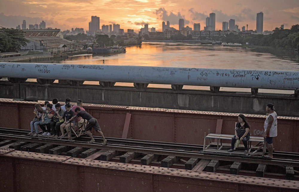 Passengers ride in foot-powered trolleys along a railroad track in Manila, giving locals a cheap and non-pollutive alternative method of transport. (AFP / NOEL CELIS)