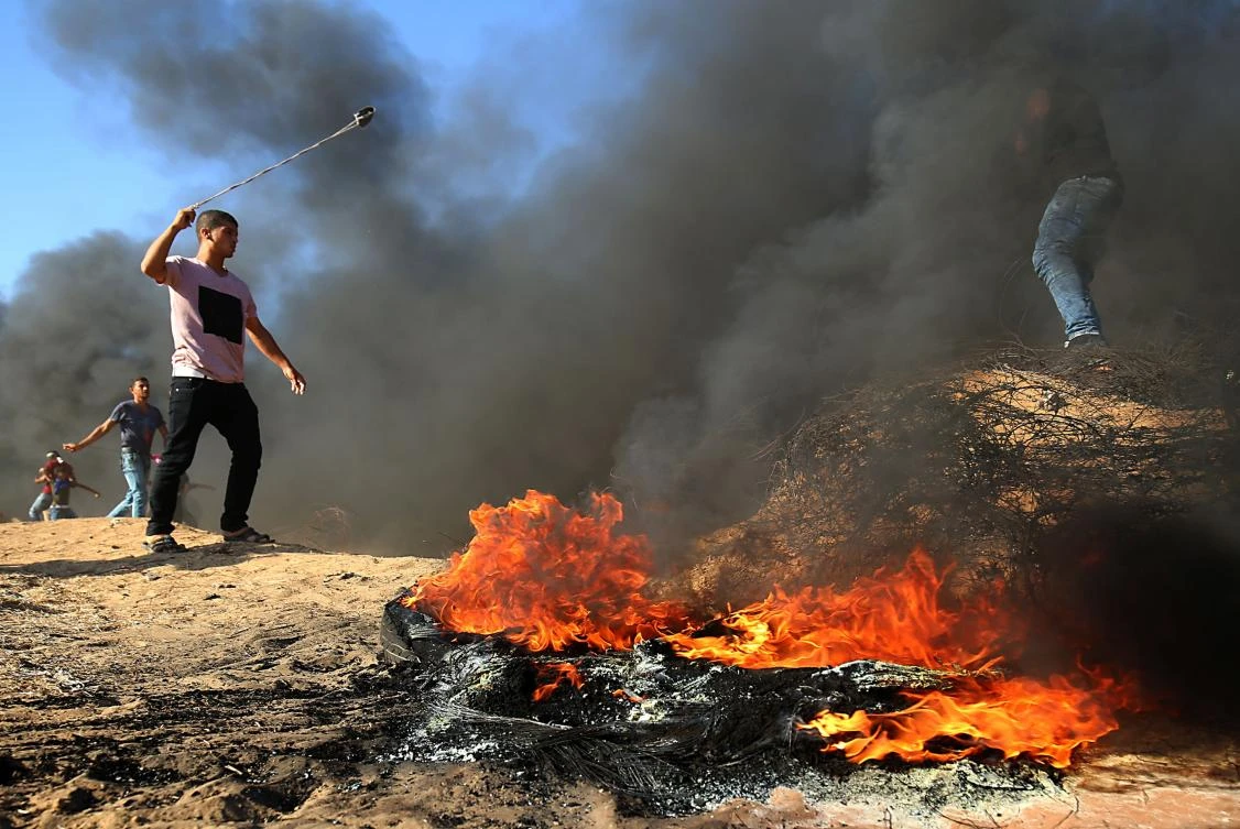 A Palestinian protester uses a slingshot next to burning tires during a demonstration at the Israel-Gaza border, east of Khan Yunis in the southern Gaza Strip on August 10, 2018. (File photo: AFP)