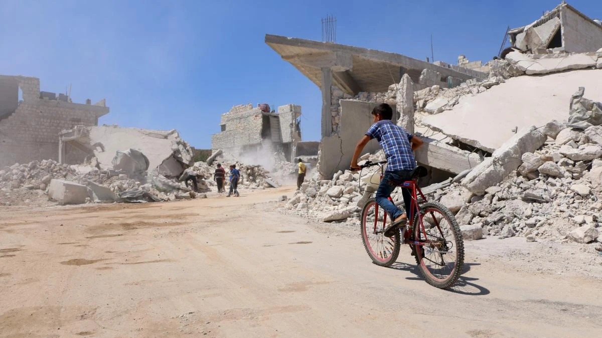 A boy rides his bicycle in a street that was destroyed during a bombardment the previous day, in the rebel-held town of Orum Al-Kubra, in the northern Syrian province of Aleppo on August 11, 2018. (AFP)