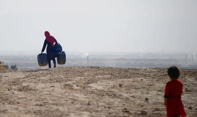 This file photo taken on July 19, 2018 shows an Afghan girl (L) carrying empty containers to collect water, as a child looks on, in Sakhi village on the outskirts of Mazar-i-Sharif. (AFP)