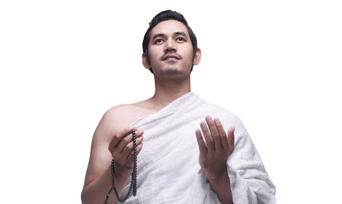 Young Asian Muslim man in ihram clothes with prayer beads. (Shutterstock)
