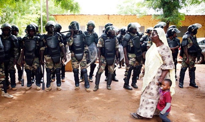 A woman walks with a child past riot police standing guard outside a polling station during a run-off presidential election in Bamako, Mali August 12, 2018. (REUTERS)