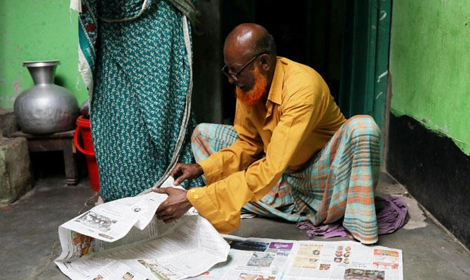 Hafiz Mia flips through the newspapers, for news of his son Riazul Islam, an alleged drug dealer who was killed by police in Tongi, Gazipur, Bangladesh, July 21, 2018. (REUTERS)