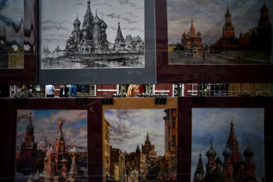 A woman walks past paintings of the Kremlin and Red Square on a street in Moscow on July 10, 2018, on the eve of the Russia 2018 World Cup semi-final football match between Croatia and England. (AFP)