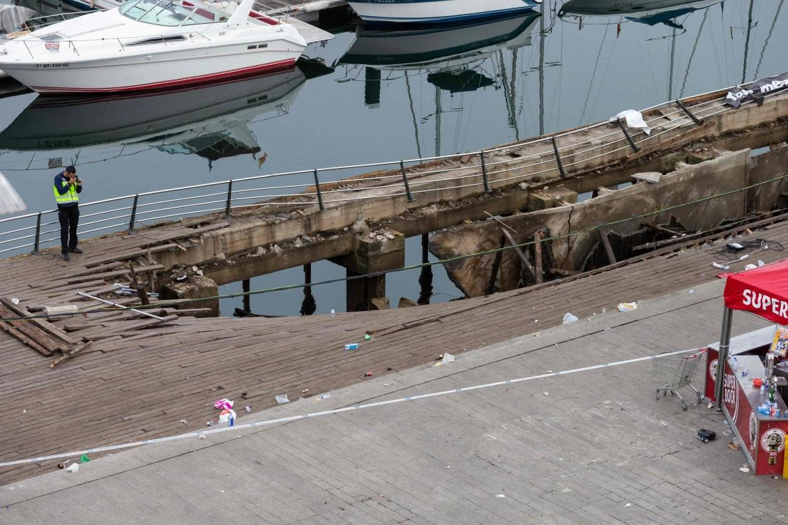 A police investigator inspects the seafront platform in Vigo on August 13, 2018 after a section of a wooden promenade suddenly collapsed with people watching a rap artist just before midnight on Sunday. (AFP)