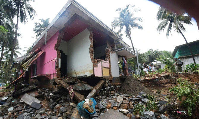 Local residents look at a partially destroyed house after heavy monsoon rains led to a landslide in Kannappankund, in the Indian state of Kerala on August 11, 2018. (AFP)