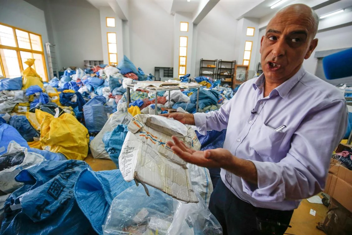 A Palestinian postal official in the West Bank city of Jericho holds up a damaged parcel, one of many items of undelivered mail, dating from as far back as 2010, which had been withheld by Israel. (AFP)