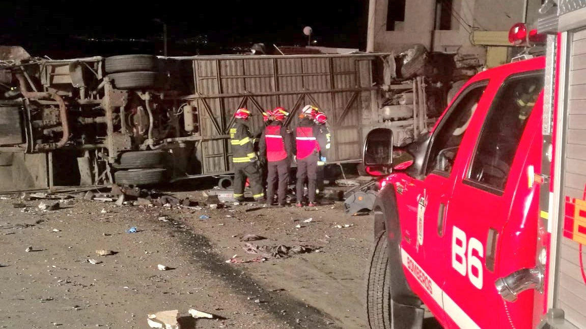 Firefighters stand next to the wreckage of a Colombian-registered bus, which was traveling to the Ecuadorean capital of Quito when it hit a smaller vehicle in an area known as dead man’s curve. (Reuters)