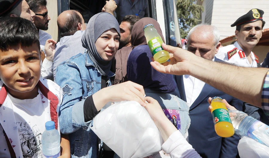 Syrian refuges receive food on their way home at the border crossing point of Jdedeh Yabous, Syria. (AP)