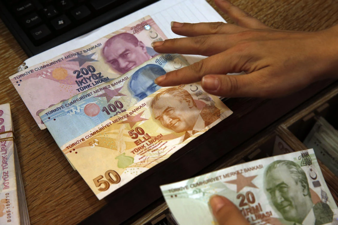 In this Wednesday, Aug. 15, 2018, file photo a worker at a currency exchange shop exhibits Turkish lira banknotes bearing pictures of modern Turkey's founder Mustafa Kemal Ataturk, in Istanbul. (AP)