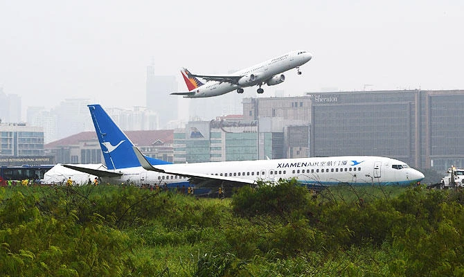 A XiamenAir Boeing 737-800 series passenger aircraft (foreground), operating as flight MF8667 from Xiamen to Manila, is seen after skidding off the runway while attempting to land in bad weather at the Manila international airport on August 17, 2018. (AFP)
