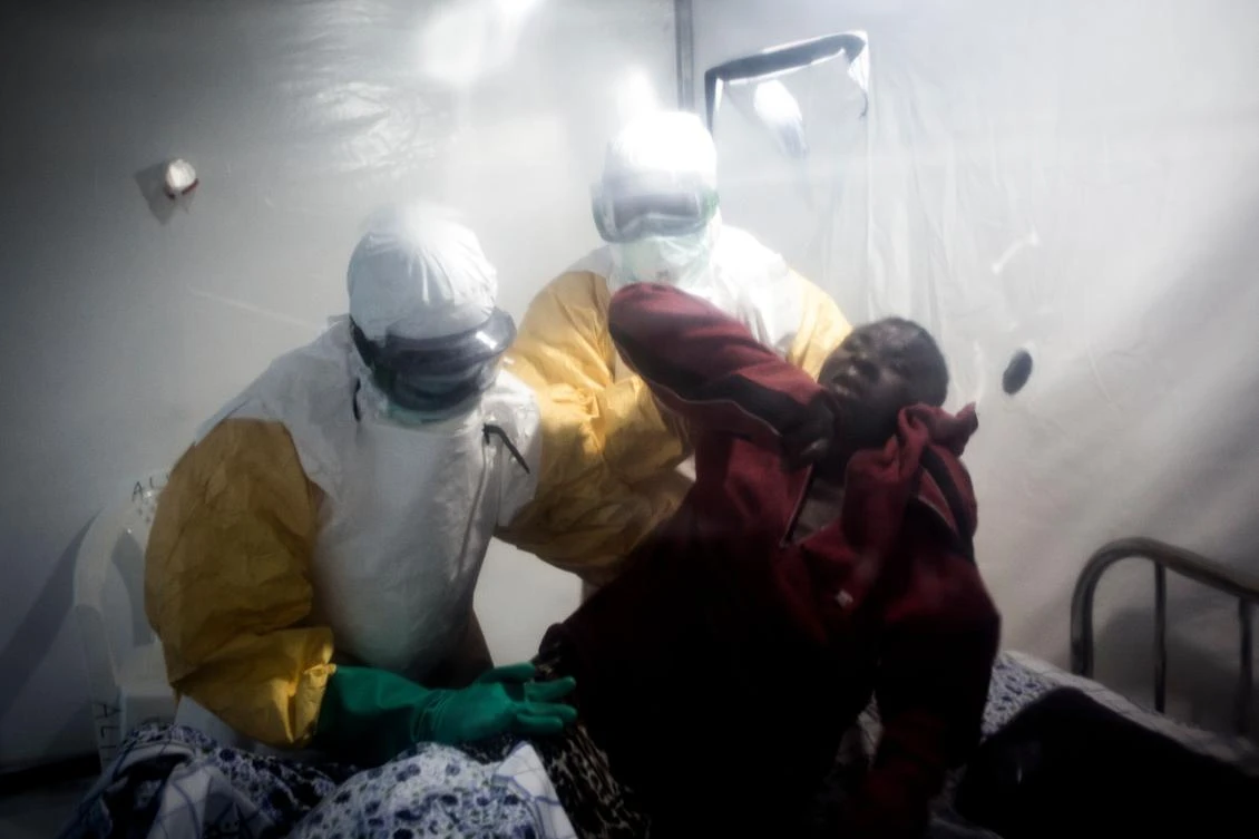 An Ebola patient is lifted up by two medical workers after being admitted into a Biosecure Emergency care Unite (CUBE) on August 15, 2018 in Beni. (AFP)