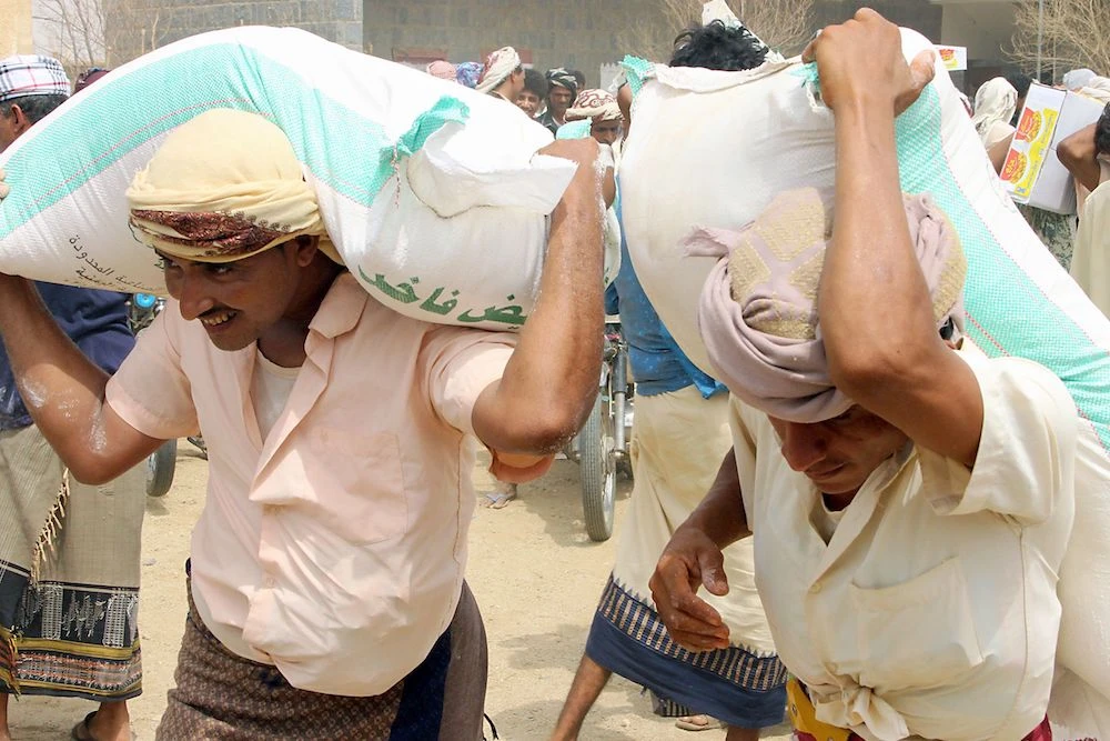 Displaced Yemenis from Hodeidah receiving food aid. The Houthis were accused of storming a World Food Program. (AFP)