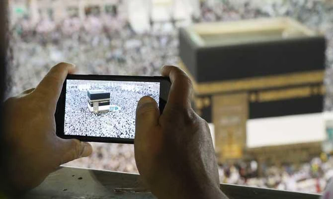 A man takes a picture of Muslim worshippers performing prayers around the Kaaba, Islam's holiest shrine, at the Grand Mosque in Saudi Arabia's holy city of Makkah on August 15, 2018, prior to the start of the annual Hajj pilgrimage in the holy city. (AFP)