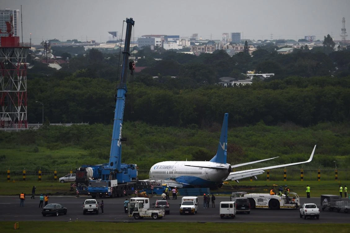 A crane prepares to lift a Xiamen Air Boeing 737-800 series passenger aircraft, operating as flight MF8667 from Xiamen to Manila, after it skidded off the runway while attempting to land in bad weather at the Manila international airport on August 17, 2018. (AFP/Ted Aljibe)