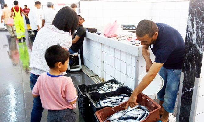 A Libyan fishmonger speaks with a customer at the Fish market in Tripoli on August 4, 2018. (AFP)