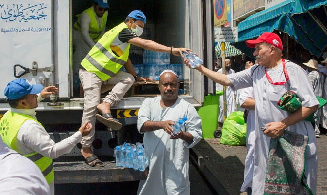 Saudi volunteers distribute water bottles among pilgrims near the Grand Mosque, ahead of the annual Hajj pilgrimage, in the Muslim holy city of Makkah, Saudi Arabia, on Saturday, Aug. 18, 2018 photo. (AP)